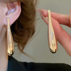 Macro detail of polished gold drop earrings showing sleek teardrop shape and glossy finish