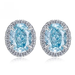 Macro shot of oval cut blue gemstone stud earrings with sparkling halo diamond setting