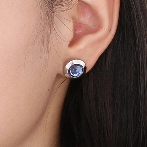 Close-up of elegant silver stainless steel stud earring with faceted blue crystal on ear