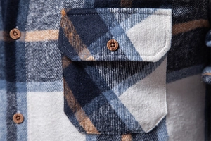 Close-up of flannel plaid shirt fabric texture with pocket and fashion button details