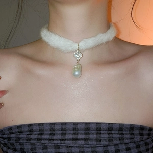 Close-up of a white plush choker featuring a rhinestone clover and large pearl pendant