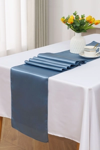 Close-up of a blue satin table runner with smooth texture and glossy finish for weddings