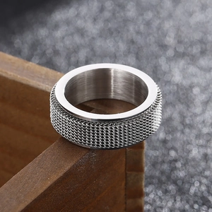Macro shot of silver stainless steel spinner ring with mesh woven texture on wood
