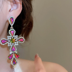 Close-up of cross earrings with colorful rhinestones and gold-plated finish
