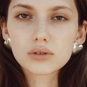 Front close-up of a model wearing large silver heart-shaped stainless steel earrings