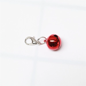 Detail of a bright red metal bell pendant with a silver lobster clasp on white background