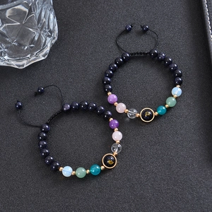 Detail of beaded zodiac bracelets with blue goldstone and colorful stones on black cord