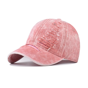 Close-up of pink distressed baseball cap showing frayed hole details and washed fabric