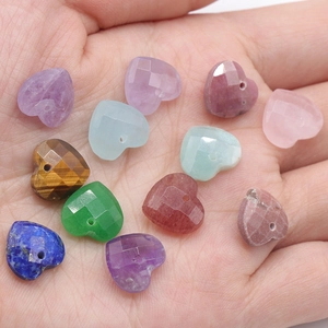 Faceted natural crystal heart pendants held in palm showing various gemstone colors