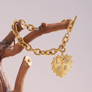 Détail d'un bracelet à gros maillons dorés 18K avec pendentif cœur LOVE sur une branche