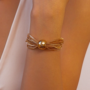 Detailed view of layered gold box chains with a polished central bead on a neck