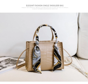 Détail de la texture crocodile sur mini sac beige avec foulard en soie sur la poignée