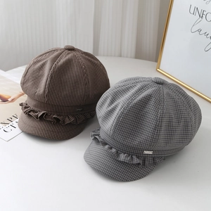 Detail view of newsboy caps with ruffled lace trim and elegant metallic plate