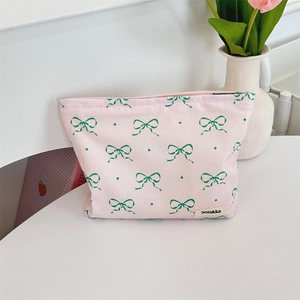 Detail of pink floral makeup bag with bow pattern and secure zipper on a white desk