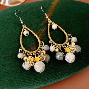Detail of bohemian teardrop earrings with beads and gold discs on green velvet