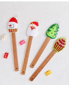 Close-up of four Christmas silicone spatulas with wooden handles on white background