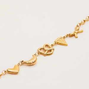 Close-up of gold heart and pretzel charms on a stainless steel charm bracelet