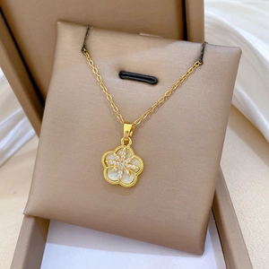 Macro detail of star-shaped zircon set in a golden five-petal flower shell necklace
