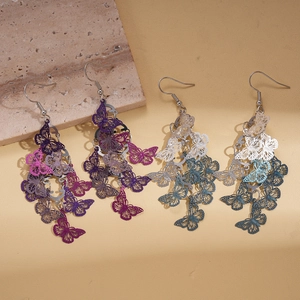 Vintage hollow butterfly tassel drop earrings in purple and teal on warm yellow background