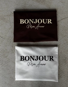 Détail de t-shirts en coton pliés marron et crème avec inscription BONJOUR imprimée