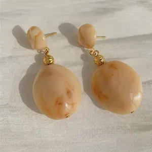 Close-up of retro beige marble resin earrings with elegant gold-tone metal accents