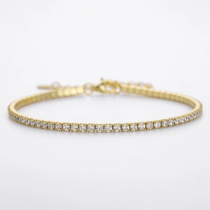 Macro shot of gold tennis bracelet featuring sparkling zircon stones and adjustable clasp