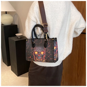 Detail of printed tote bag featuring skull and flame pattern with gold metal hardware