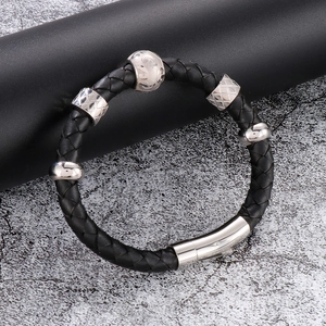 Détail macro du bracelet en cuir tressé noir avec fermoir en titane et perles argentées
