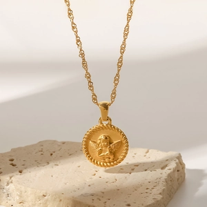 Detail of gold angel relief pendant on a minimalist water wave chain over beige stone