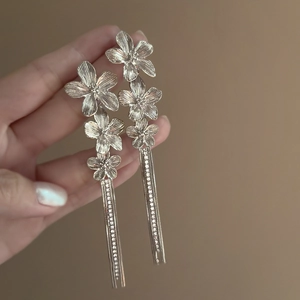 Detail of elegant gold floral tassel earrings with micro-set zircon and long chain dangles