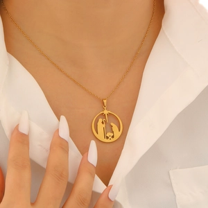 Close-up of 18K gold plated nativity scene pendant necklace worn on a model's collarbone