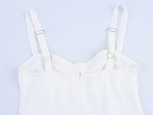 Detail of adjustable straps and metal rings on a white tiered dress with back zipper