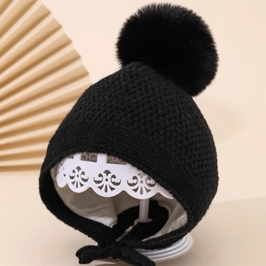 Detail der Baby-Strickmütze mit warmem Futter, Ohrenklappen und großem Kunstfell-Bommel