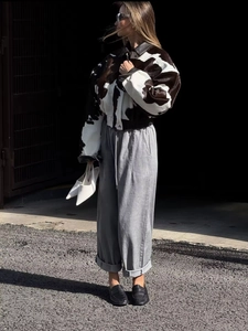 Detailed view of women's short cow print faux fur jacket and grey wide-leg drawstring pants