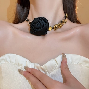 Primo piano di un girocollo in raso nero vintage con fiori dorati e dettagli in perle