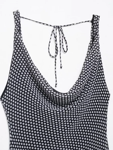 Detailed view of the cowl neck design and black polka dot pattern on the white dress
