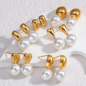 Detailed view of six pairs of elegant gold pearl earrings on a white stone background