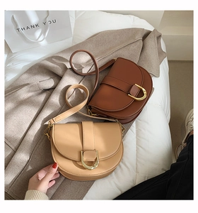 Gros plan de sacs de selle vintage en cuir caramel et abricot avec boucles dorées en D