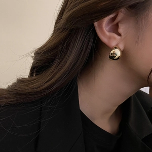 Close-up of a model wearing minimalist chunky gold dome earrings with a polished finish