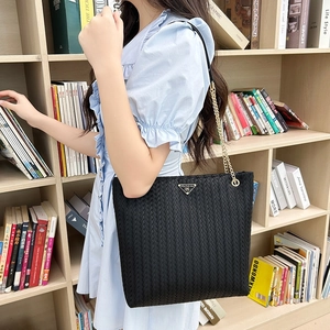 Black woven texture tote bag with chain strap and triangle detail on model