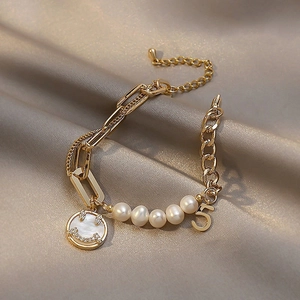 Elegant gold pearl bracelet with smiley face and number five charms on silk background
