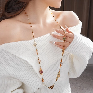Détail d'un collier géométrique en céramique marron avec perles de cristal et pendentif papillon