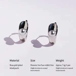 Polished silver hoops with grey pearls creating a heart-shaped shadow on white background