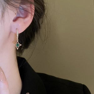Gros plan de boucles d'oreilles étoile vintage dorées avec zircon vert et détails