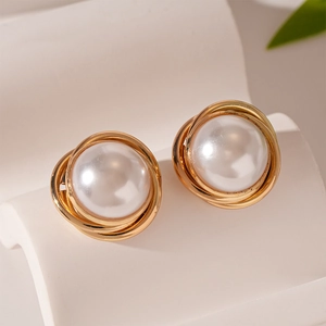 Vue macro de boucles d'oreilles rondes dorées vintage avec perle blanche élégante au centre