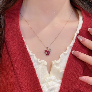 Detail of red enamel gourd pendant necklace with small coin charm on model
