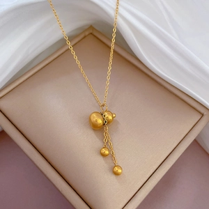 Detail of a gold gourd pendant necklace on a beige jewelry box with white silk