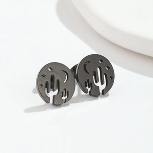 Detail of matte black earring with cutout cactus, crescent moon and star patterns