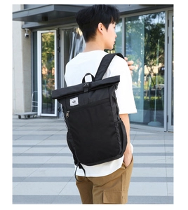 Outdoor view of a black roll-top waterproof backpack for business and travel use