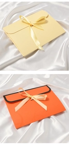 Elegant envelope gift boxes in beige and orange with silk ribbons on white satin